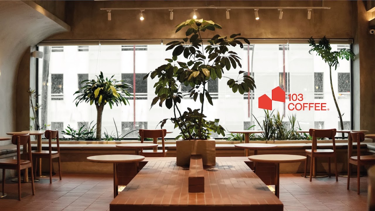 103 Coffee Sri Petaling interior — terrazzo counter, plants, and the red 103 logomark on the window
