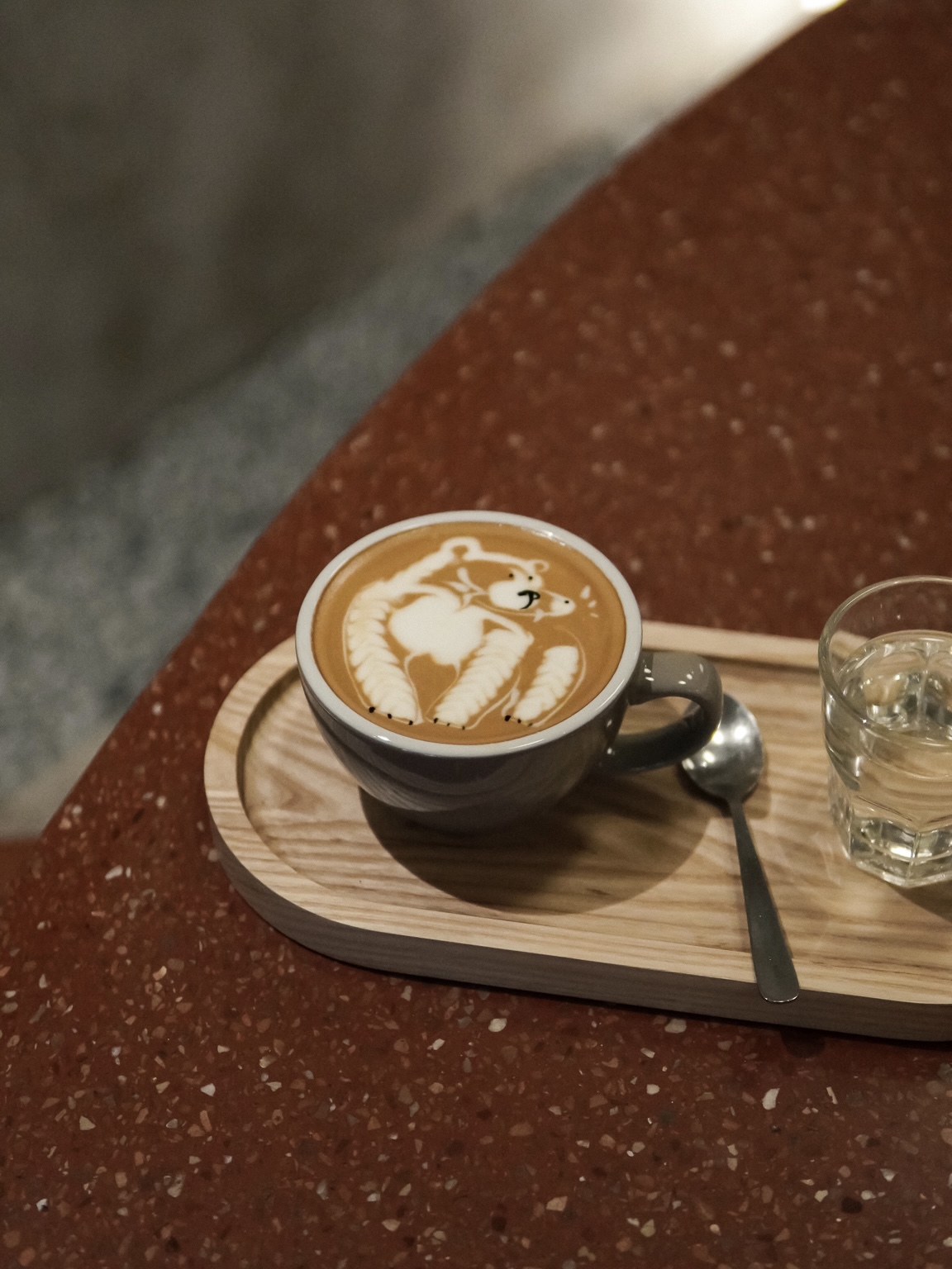 Latte art shaped like a bear on the terrazzo table at 103 Coffee