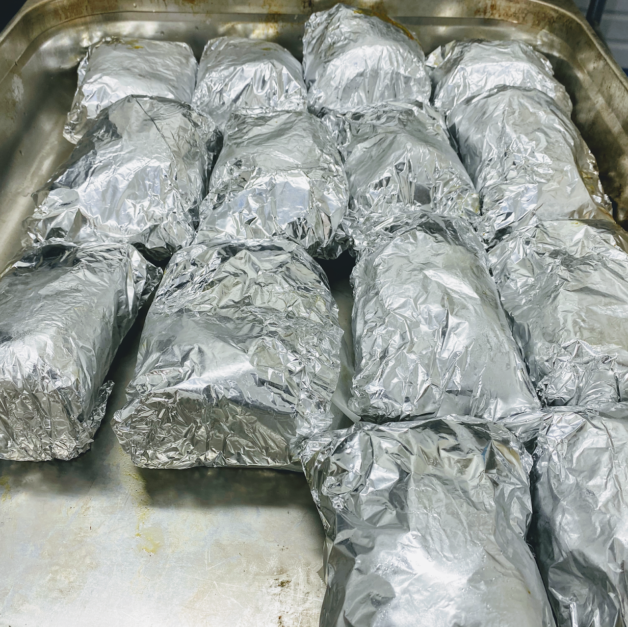 Foil-wrapped shawarma rolls fresh off the grill