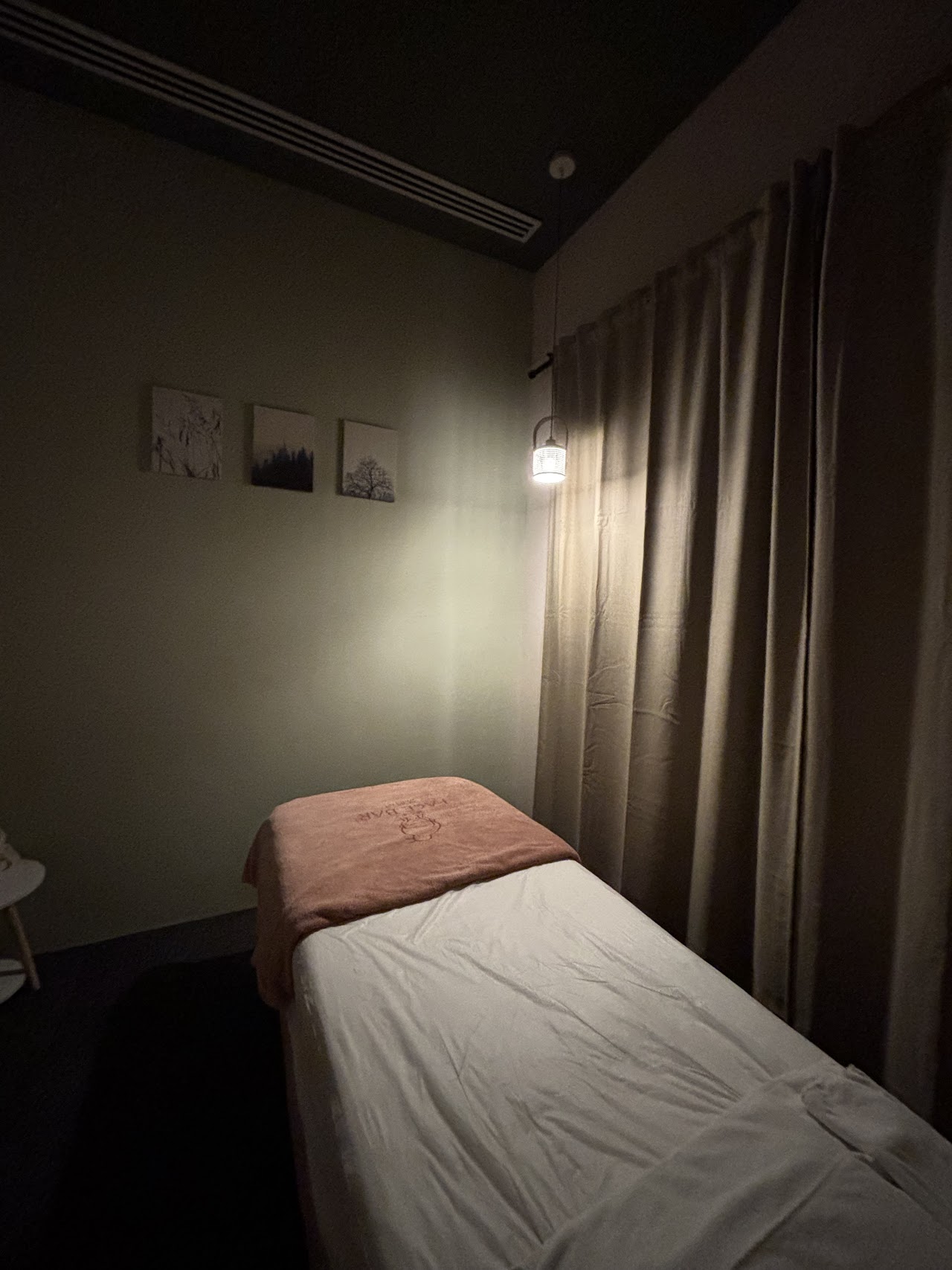 A dim, private Face Bar treatment room with a branded towel on the treatment bed