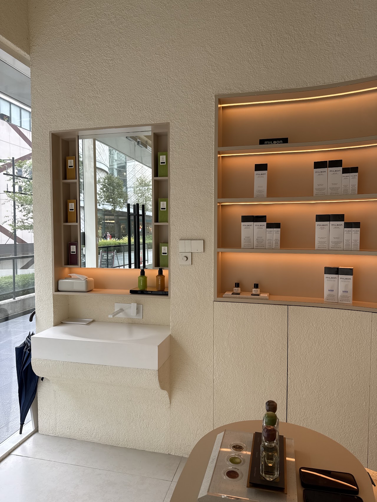 Curved millwork basin and backlit product shelving at Her Maison