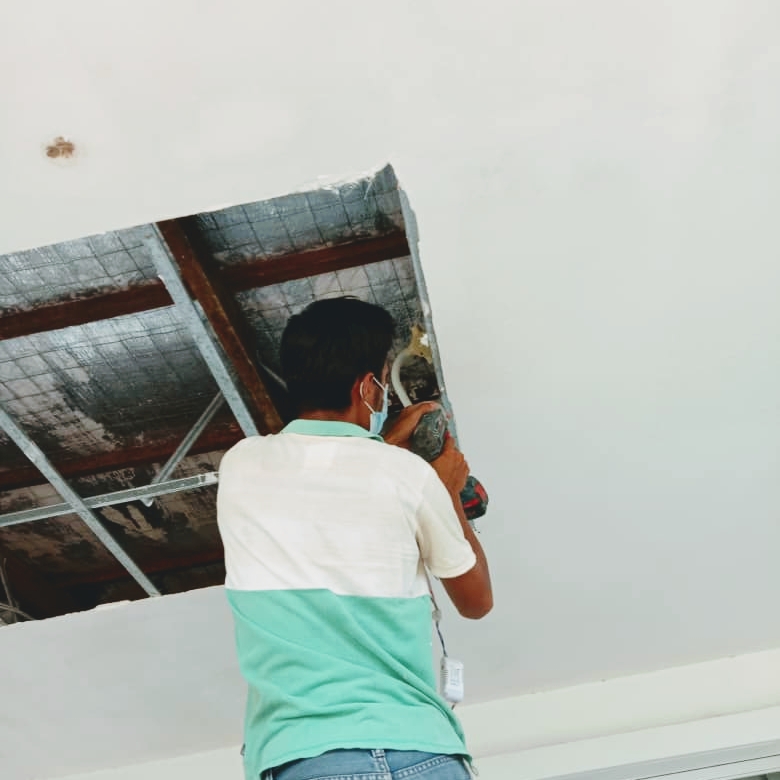 Technician accessing ceiling wiring