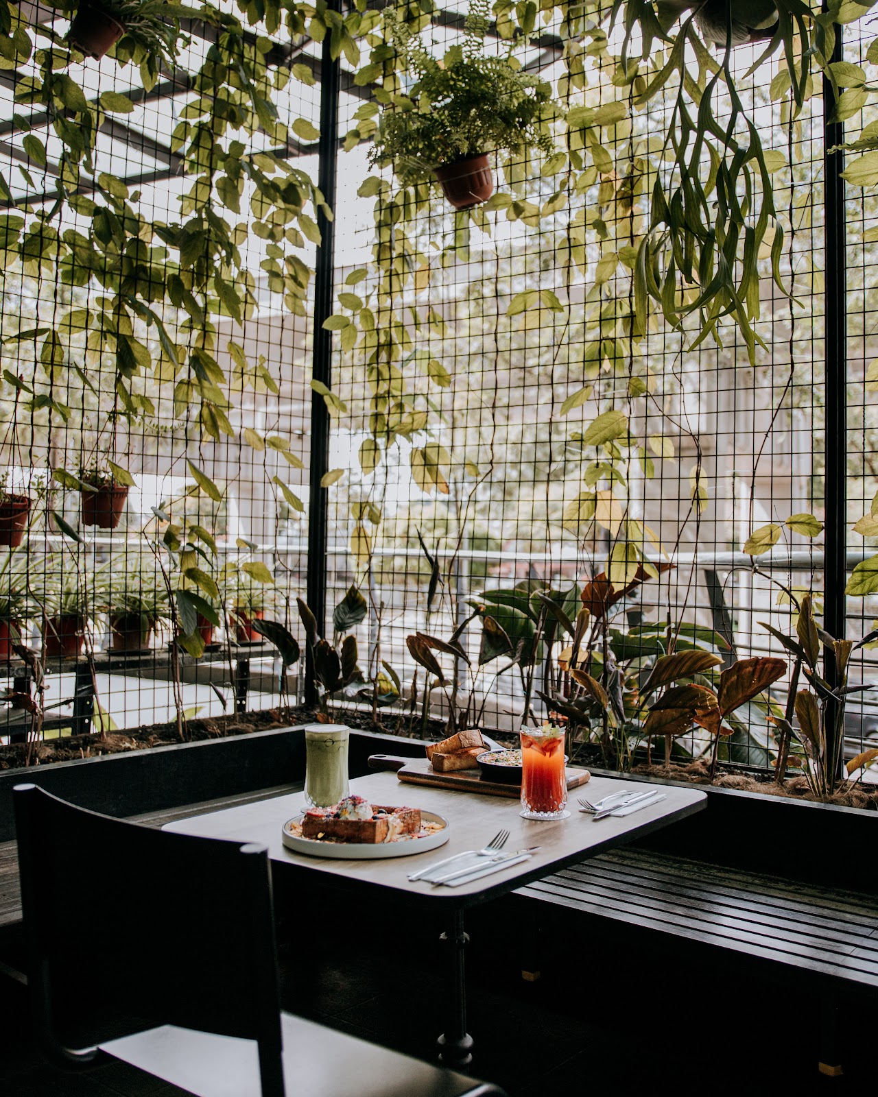 Naj & Belle Cafe SS15 Courtyard — plant-wall greenhouse seating with brunch table